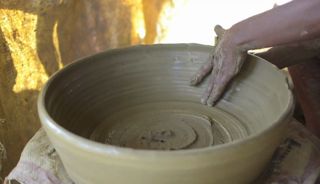 CLAY POT takes shape on a potter's wheel.